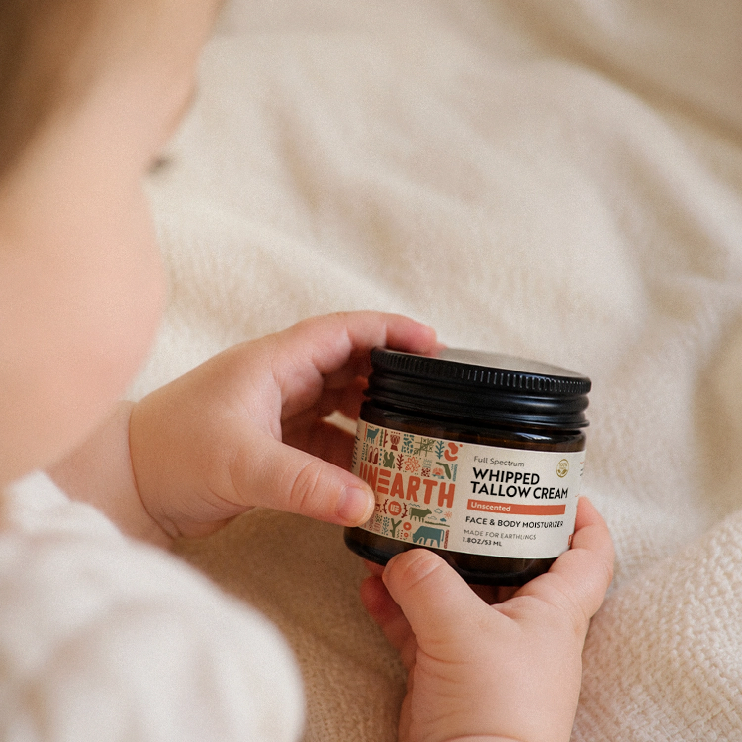 Baby holding a jar of Unearth Whipped Tallow Cream